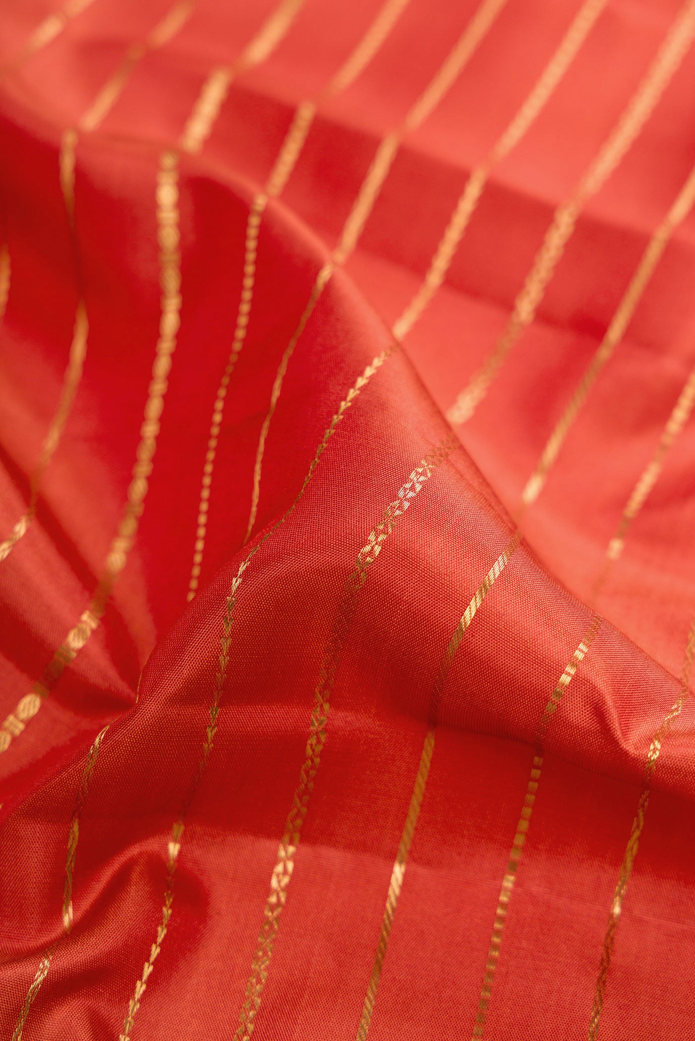 Close up of Brick Orange Kanjivaram Silk Saree with Stripes on the body and Zari Border.  displaying folds