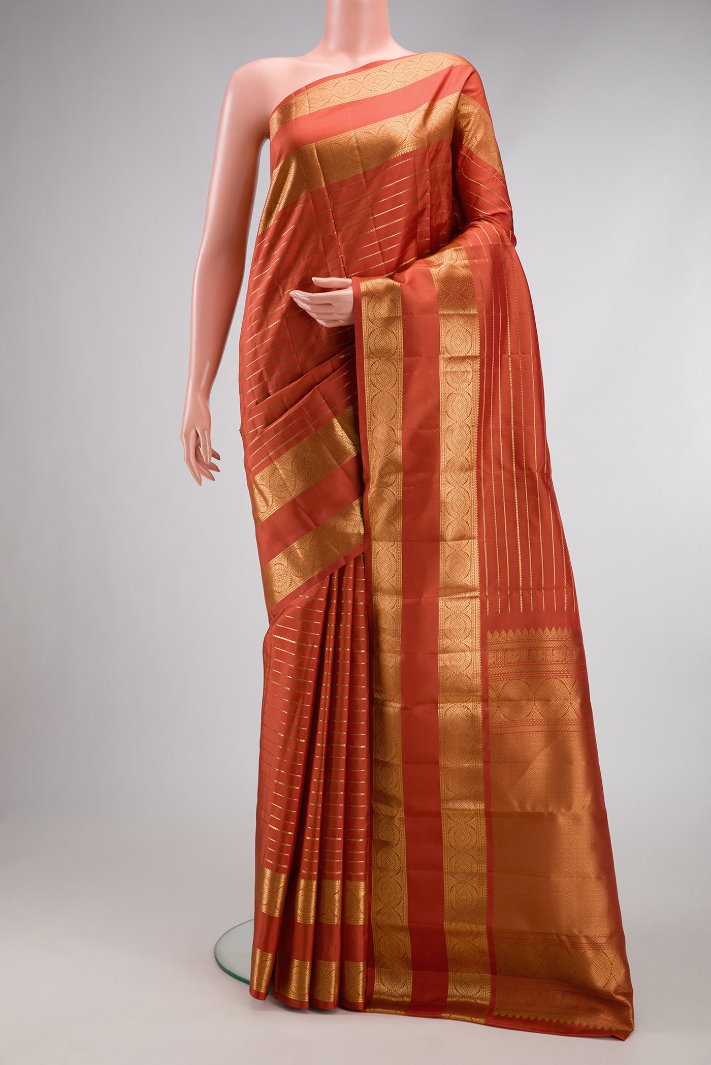 Brick Orange Kanjivaram Silk Saree with Stripes on the body and Zari Border.  displayed on a mannequin