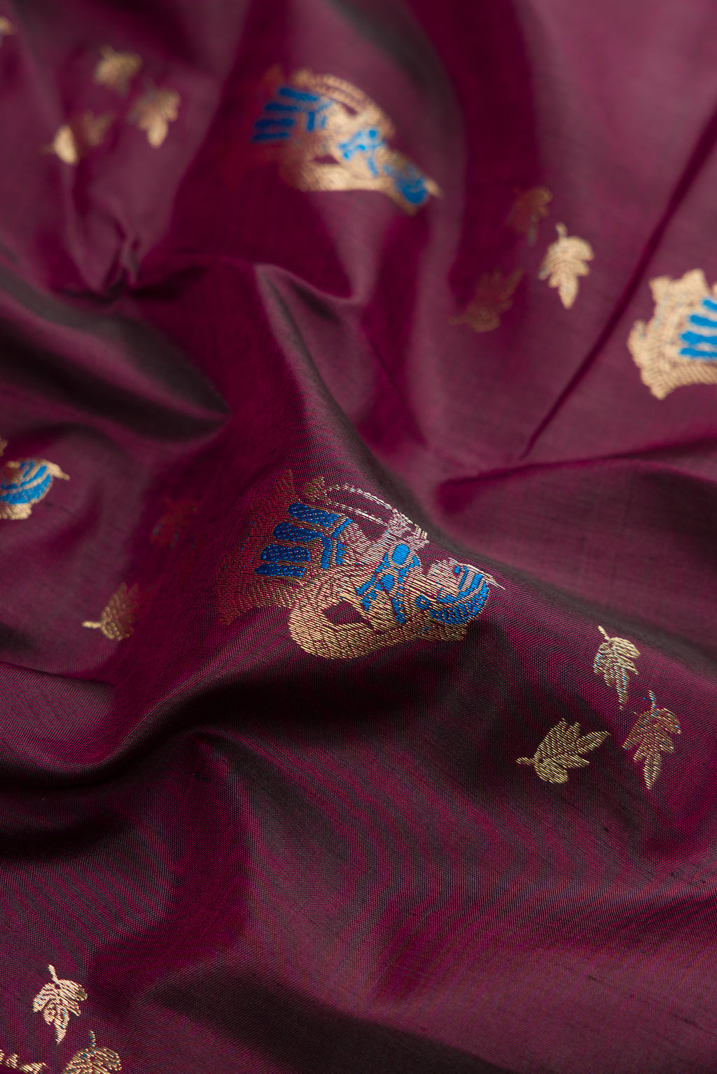 Close up of Burgundy Baluchari Silk Saree with Zari And Thread Butta on the body and Fancy Border.  displaying folds