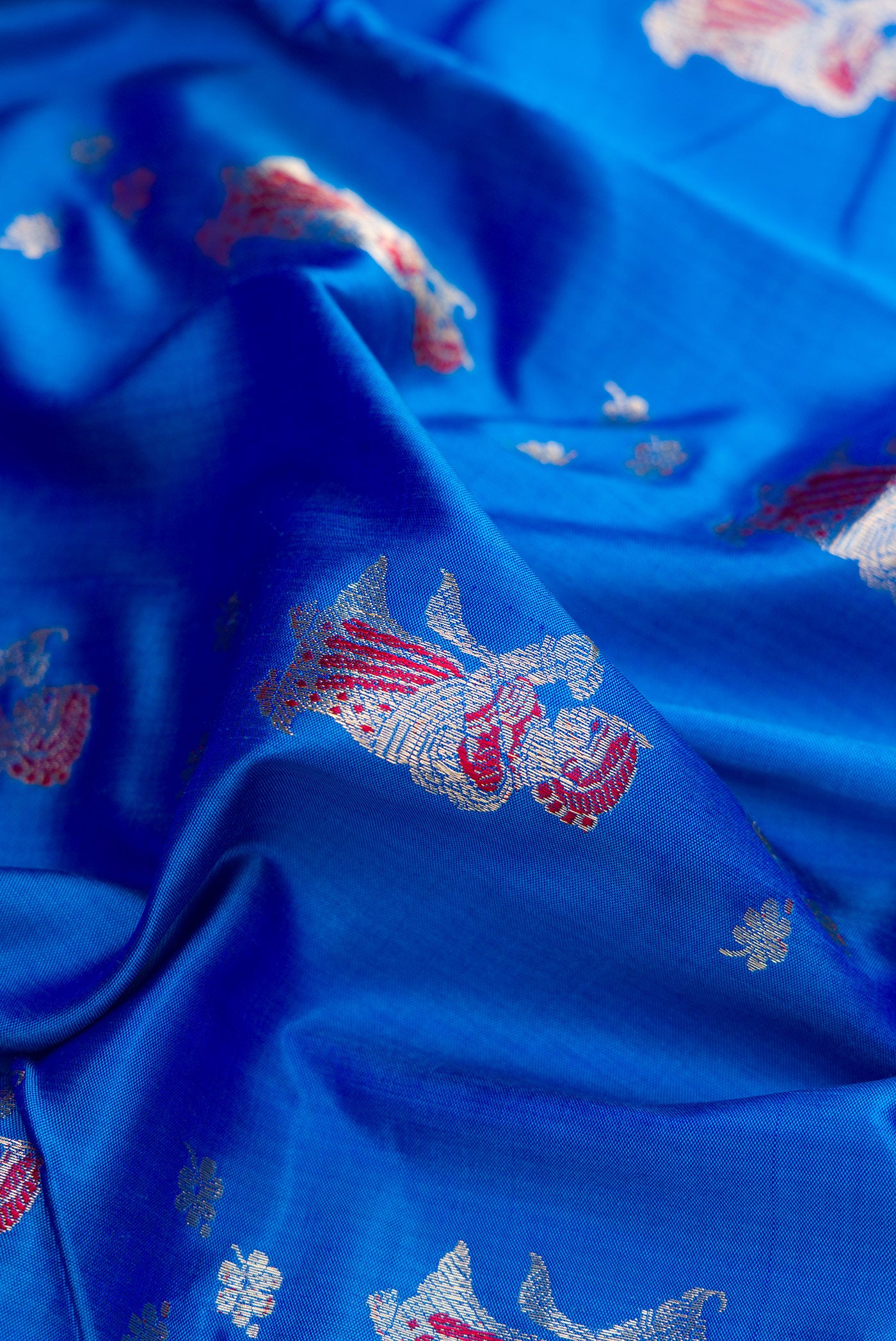 Close up of Royal Blue Dual Tone Baluchari Silk Saree with Zari And Thread Butta on the body and Fancy Border.  displaying folds