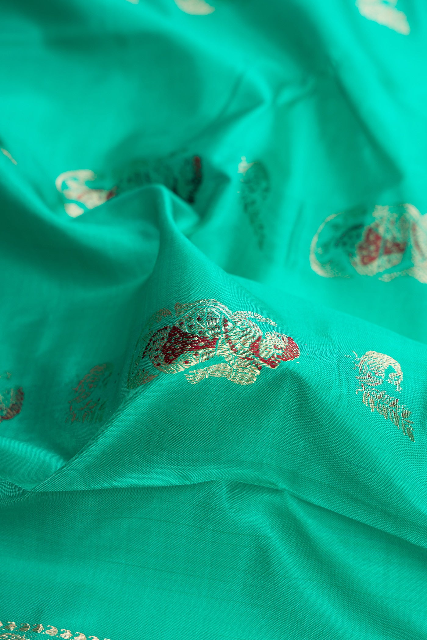 Close up of Sea Green Dual Tone Baluchari Silk Saree with Zari And Thread Butta on the body and Fancy Border.  displaying folds