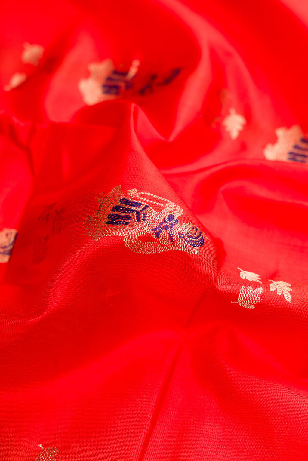 Close up of Orange Baluchari Silk Saree with Zari And Thread Butta on the body and Fancy Border.  displaying folds