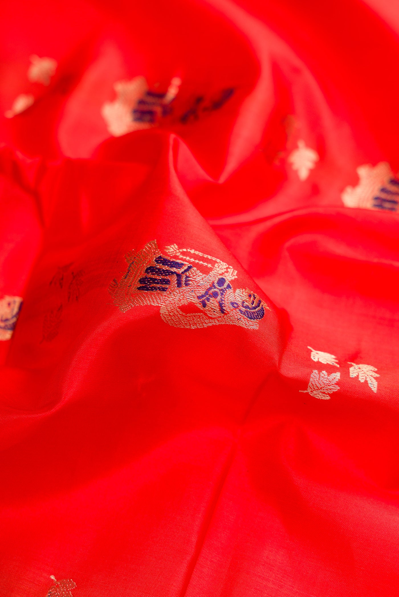 Close up of Orange Baluchari Silk Saree with Zari And Thread Butta on the body and Fancy Border.  displaying folds