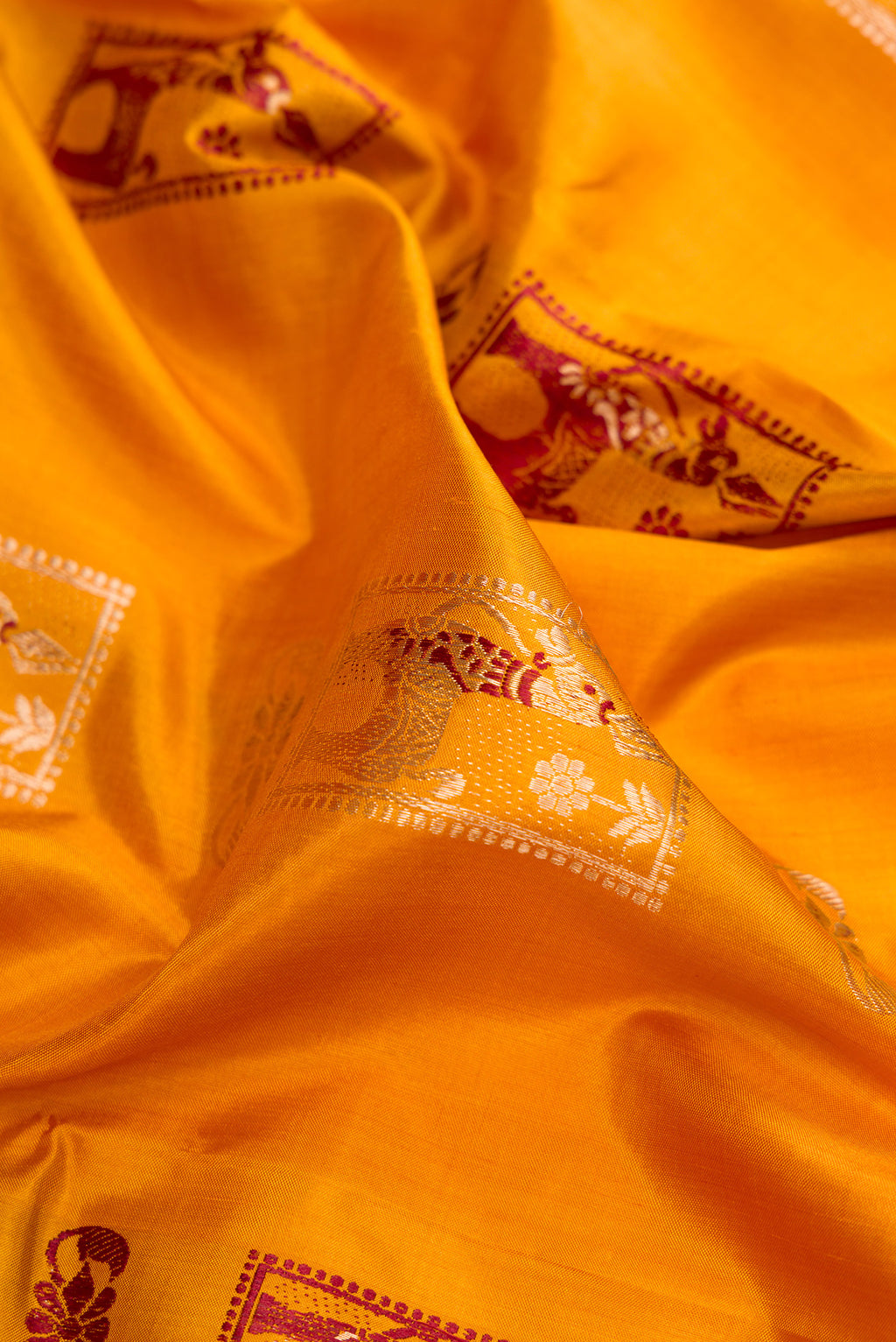 Close up of Mustard Baluchari Silk Saree with Zari And Thread Butta on the body and Zari Border.  displaying folds