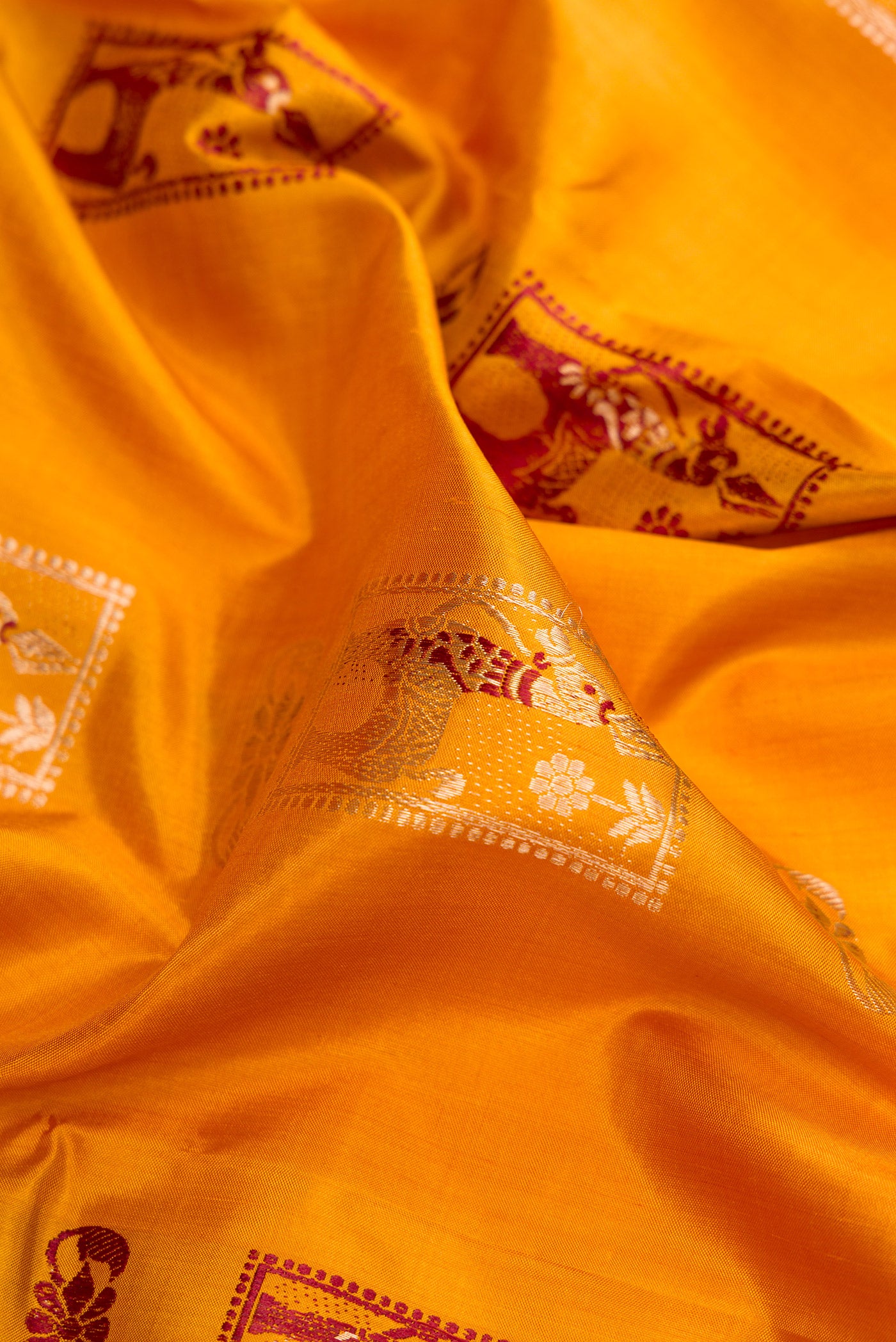 Close up of Mustard Baluchari Silk Saree with Zari And Thread Butta on the body and Zari Border.  displaying folds