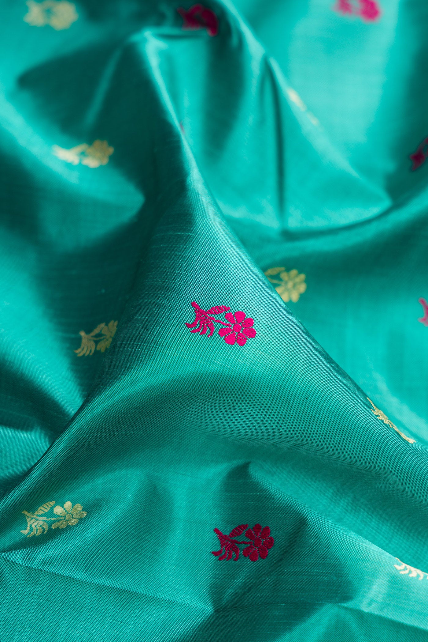 Close up of Turquoise Baluchari Silk Saree with Thread Butta on the body and Thread Border.  displaying folds