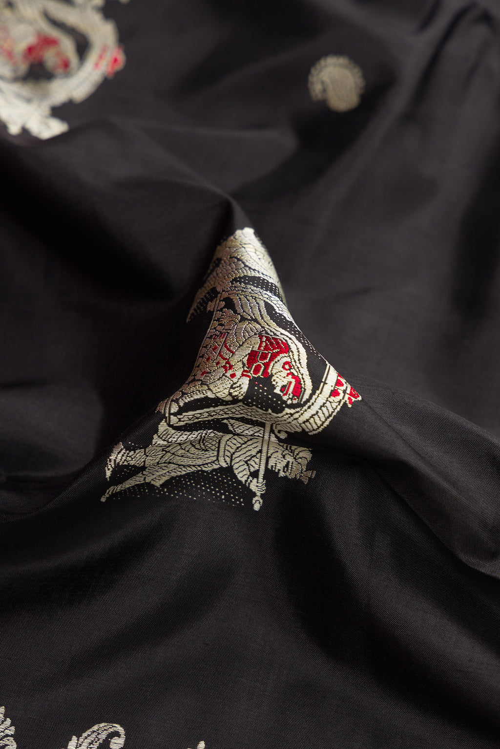 Close up of Black Baluchari Silk Saree with Thread Butta on the body and Thread Border.  displaying folds