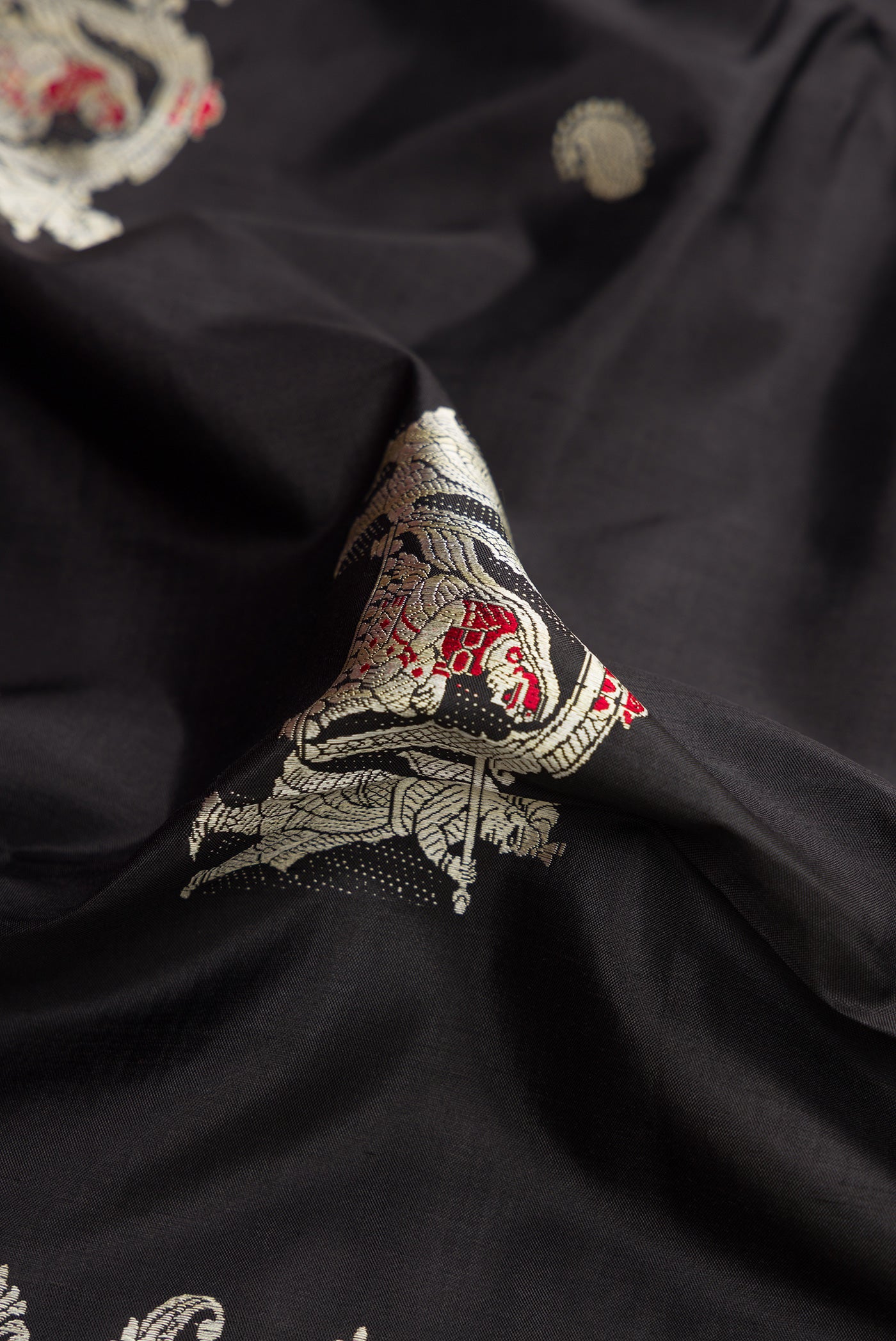 Close up of Black Baluchari Silk Saree with Thread Butta on the body and Thread Border.  displaying folds