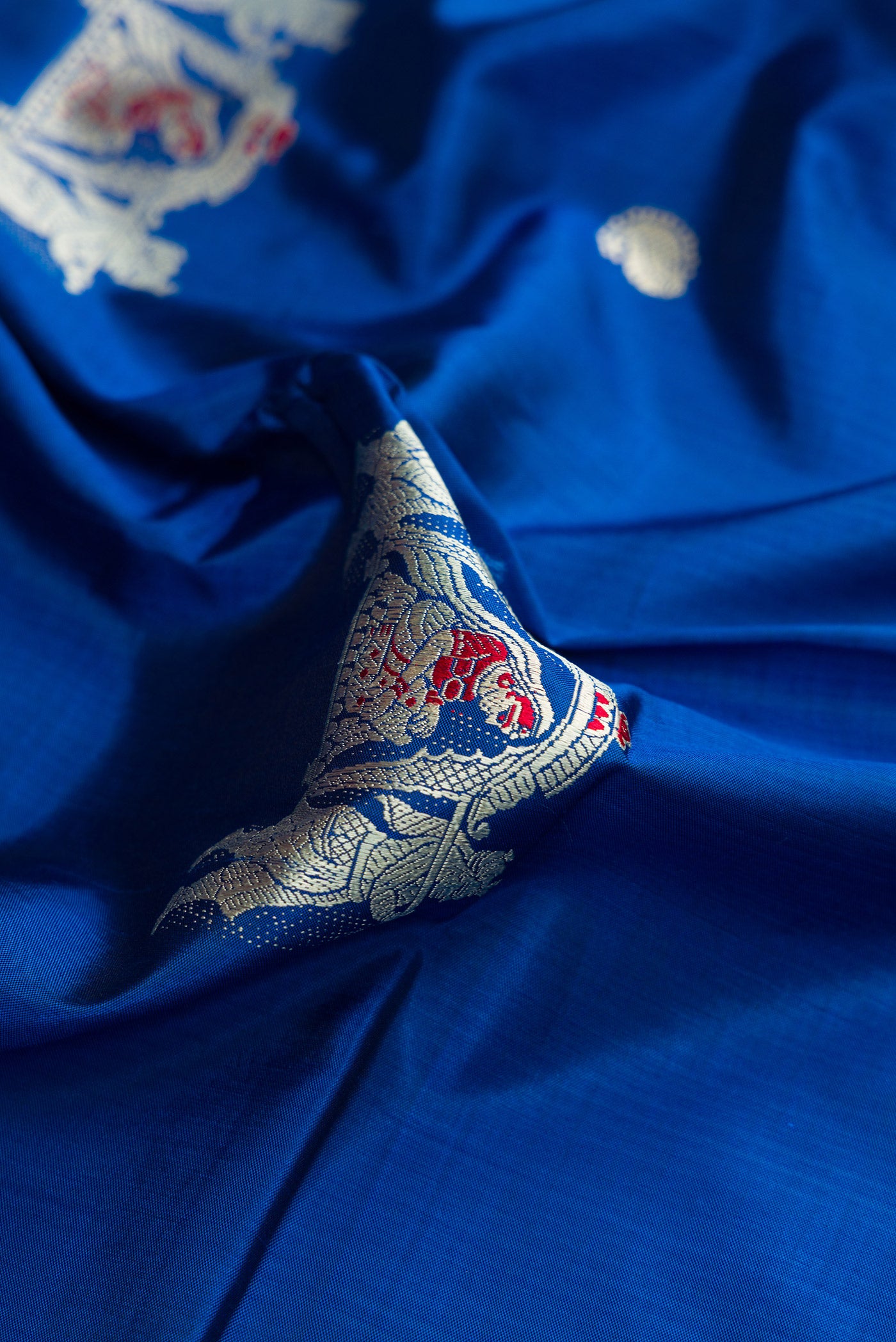 Close up of Royal Blue Dual Tone Baluchari Silk Saree with Thread Butta on the body and Thread Border.  displaying folds