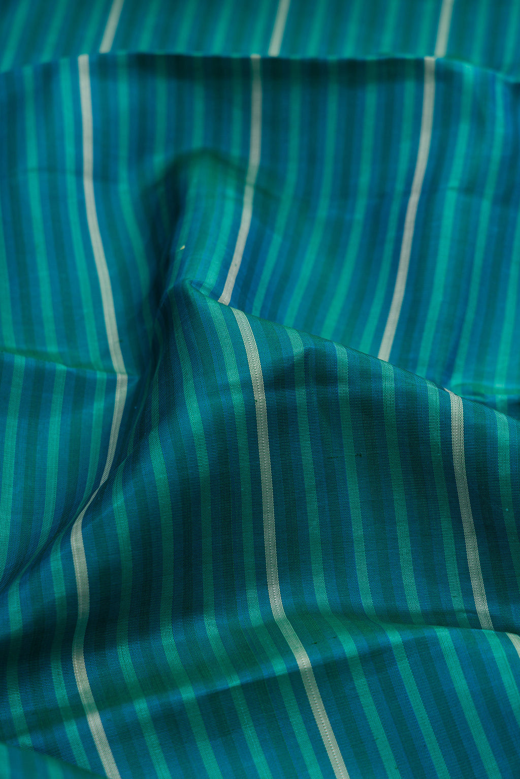 Close up of Peacock Blue Kanjivaram Silk Saree with Stripes on the body and Fancy Border.  displaying folds