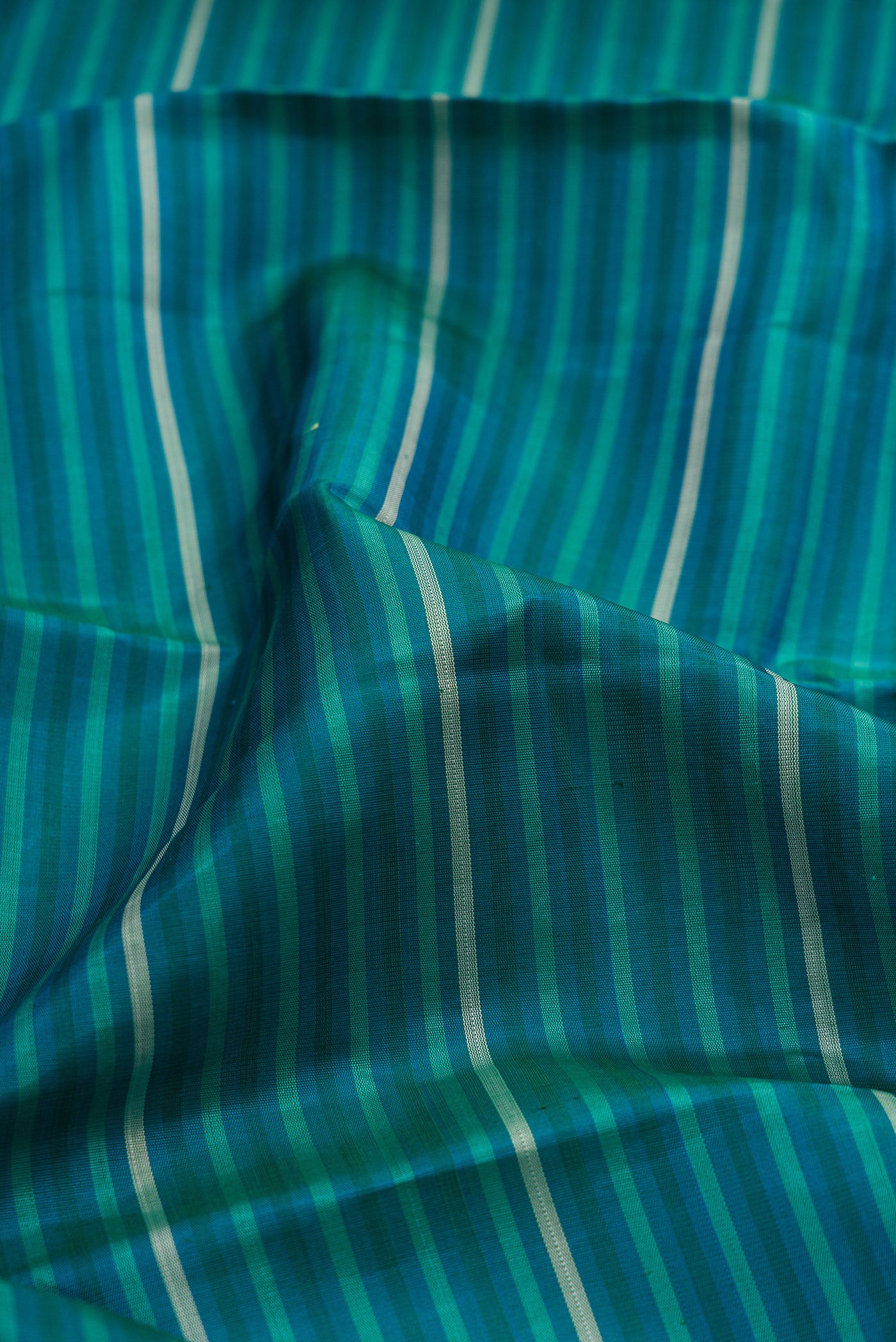Close up of Peacock Blue Kanjivaram Silk Saree with Stripes on the body and Fancy Border.  displaying folds