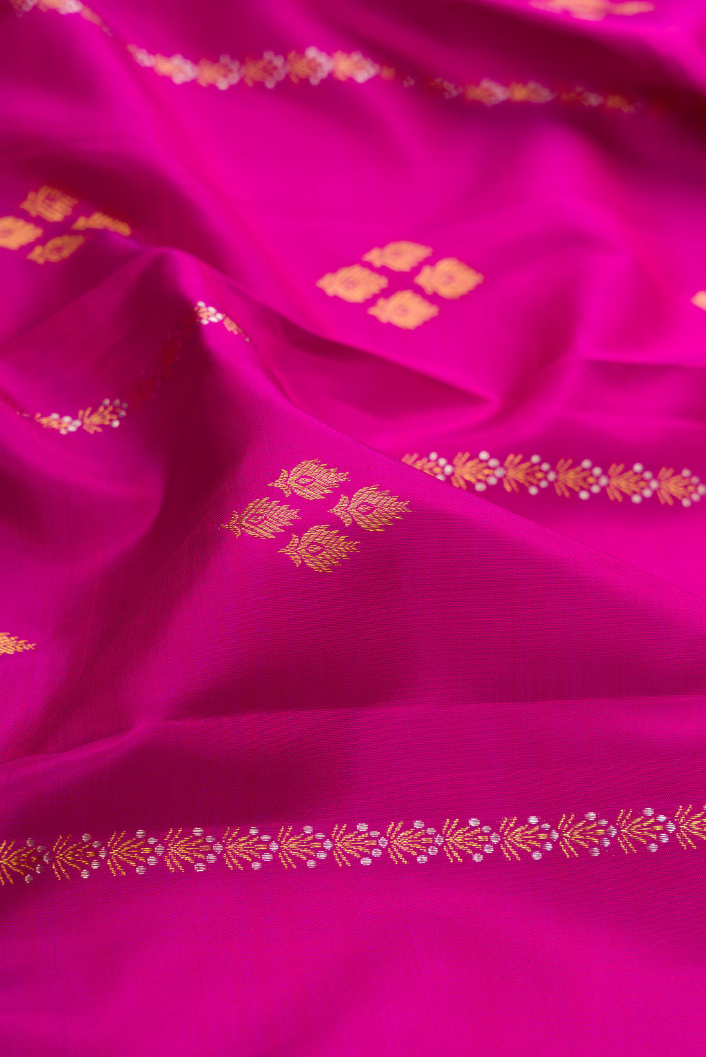 Close up of Magenta Kanjivaram Silk Saree with Zari Butta on the body and Zari Border.  displaying folds
