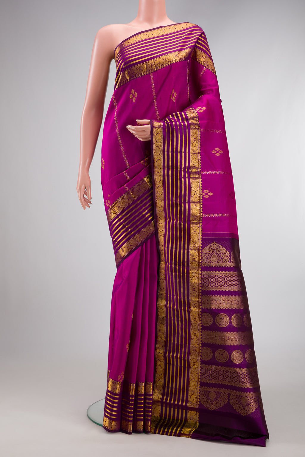 Magenta Kanjivaram Silk Saree with Zari Butta on the body and Zari Border.  displayed on a mannequin