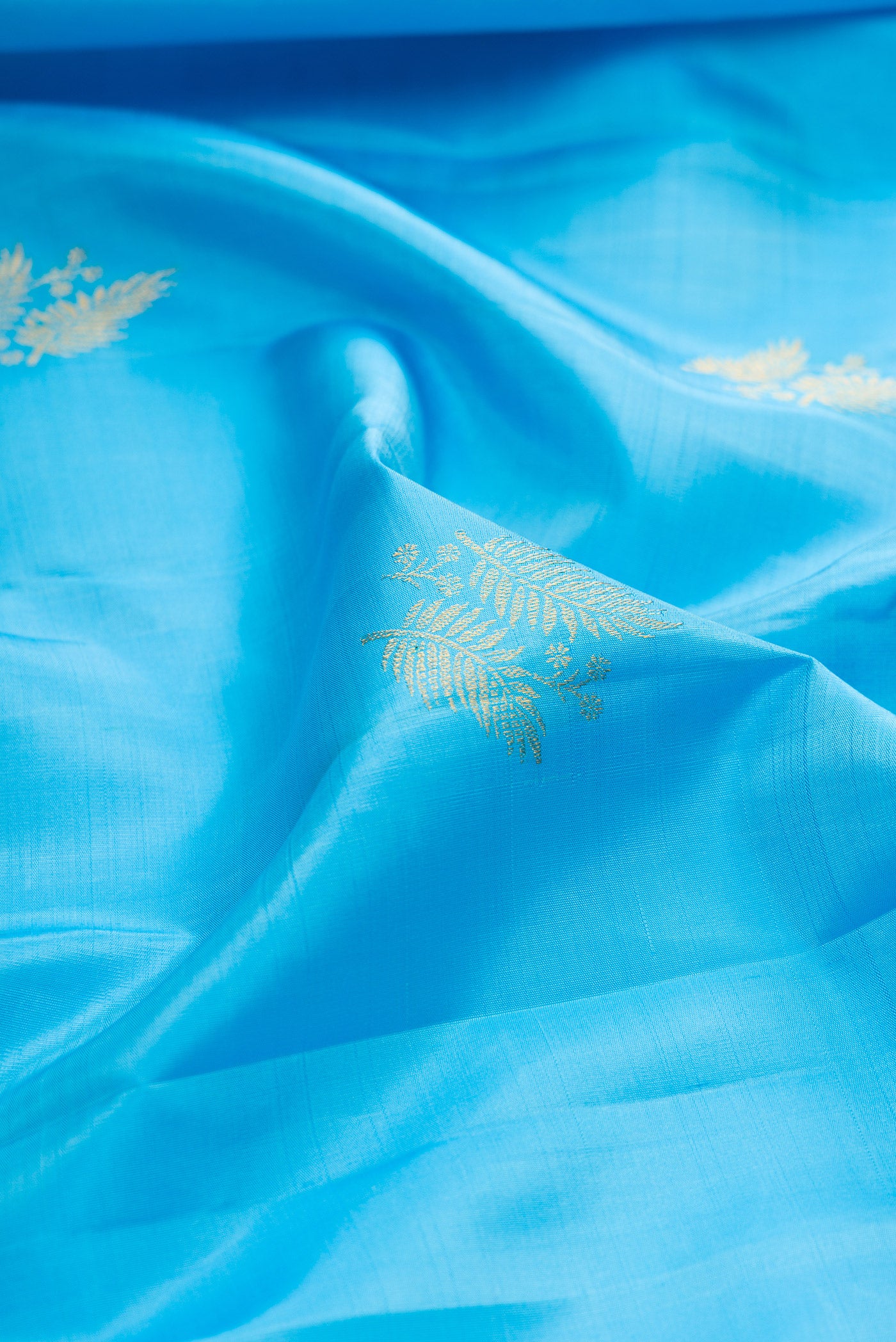 Close up of Sky Blue Kanjivaram Silk Saree with Zari Butta on the body and Zari Border.  displaying folds
