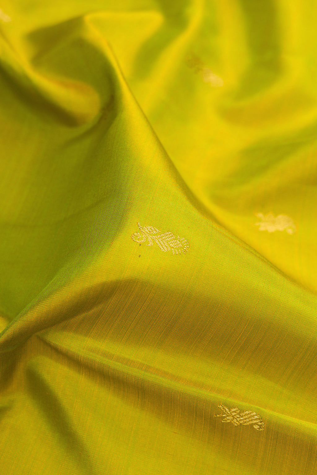 Close up of Parrot Green Kanjivaram Silk Saree with Zari Butta on the body and Zari Border.  displaying folds