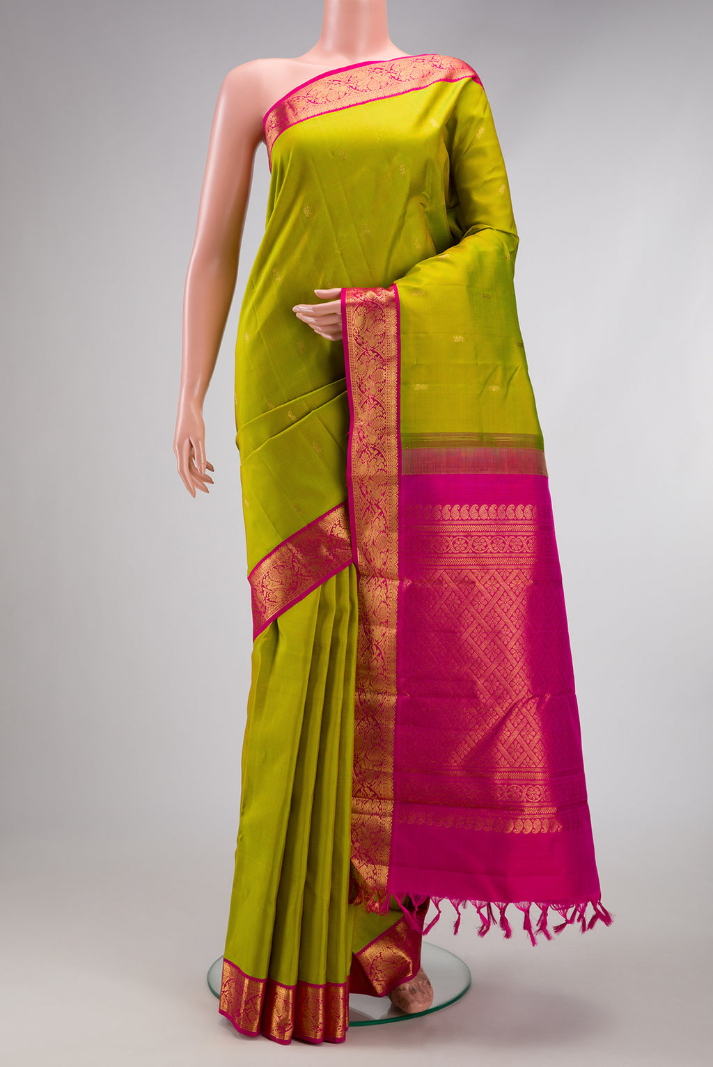 Parrot Green Kanjivaram Silk Saree with Zari Butta on the body and Zari Border.  displayed on a mannequin