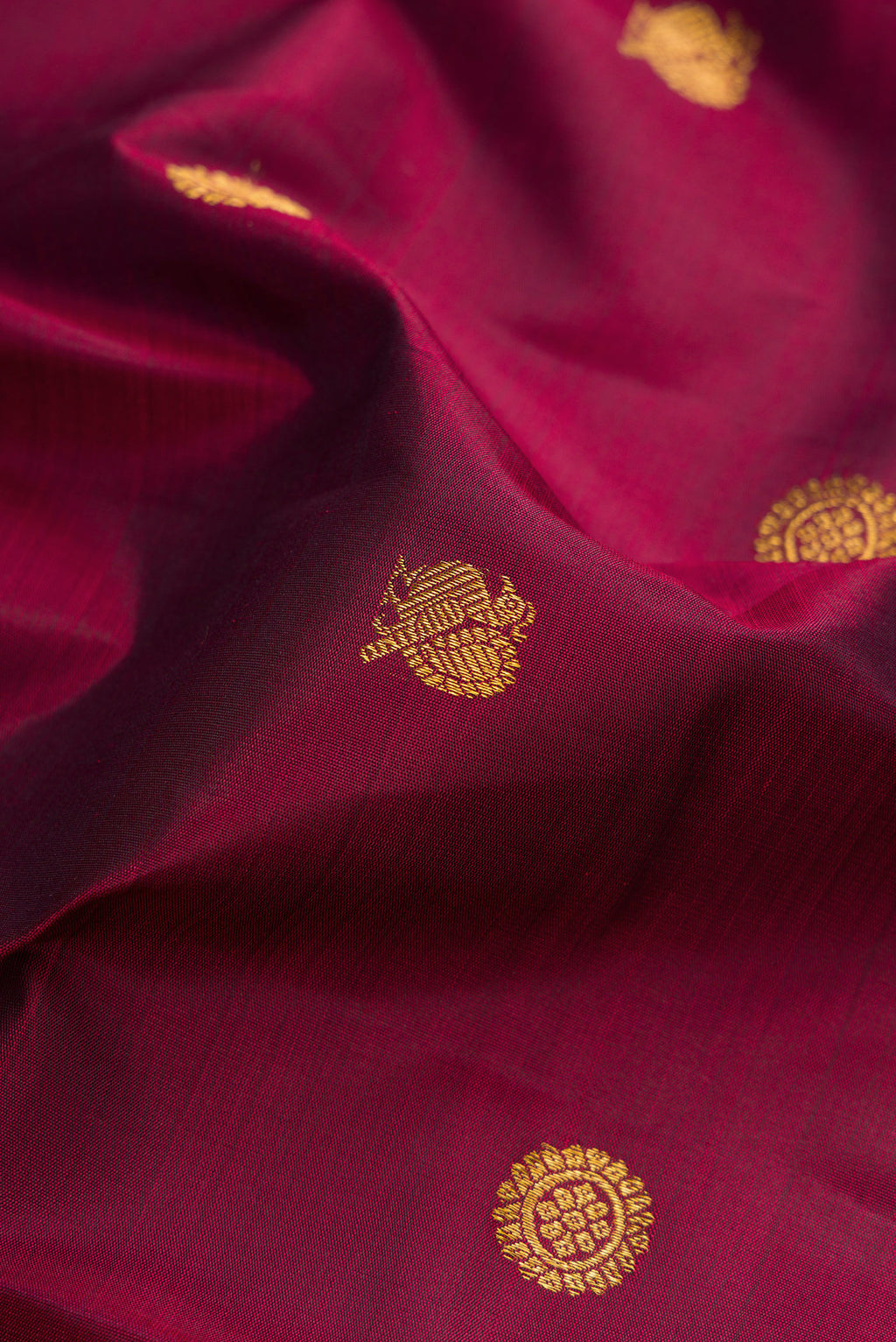 Close up of Maroon Kanjivaram Silk Saree with Zari Butta on the body and Zari Border.  displaying folds