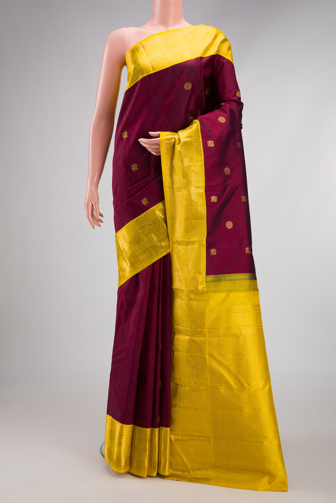 Maroon Kanjivaram Silk Saree with Zari Butta on the body and Zari Border.  displayed on a mannequin
