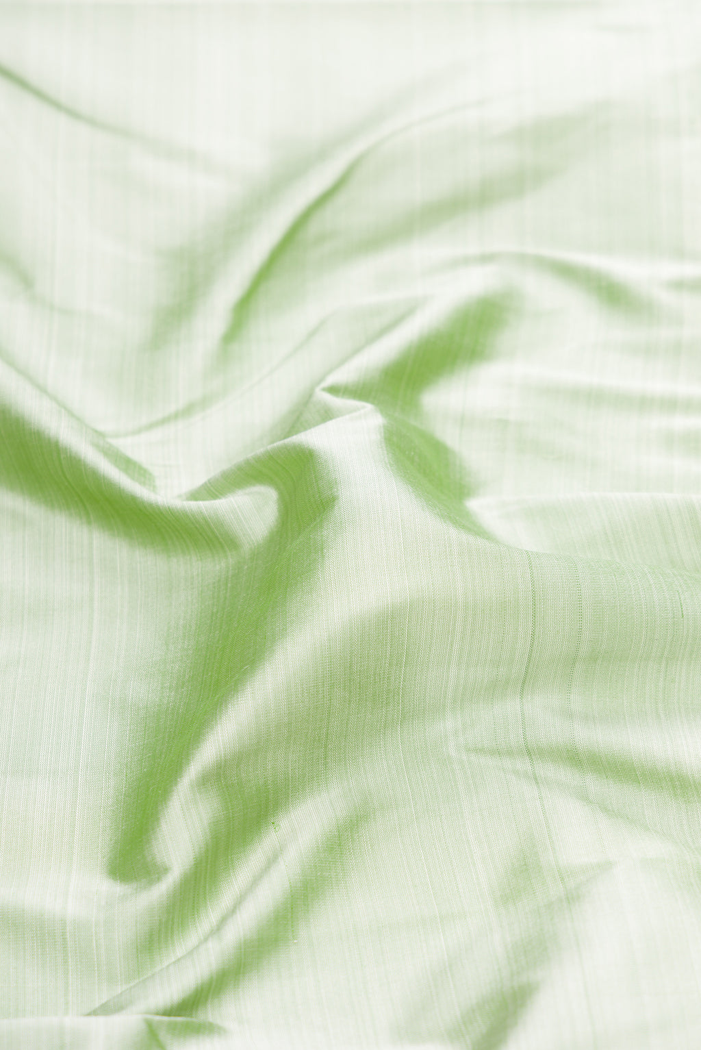 Close up of Pista Green Kanchipuram Silk Saree with Plain Body and Zari Border.  displaying folds
