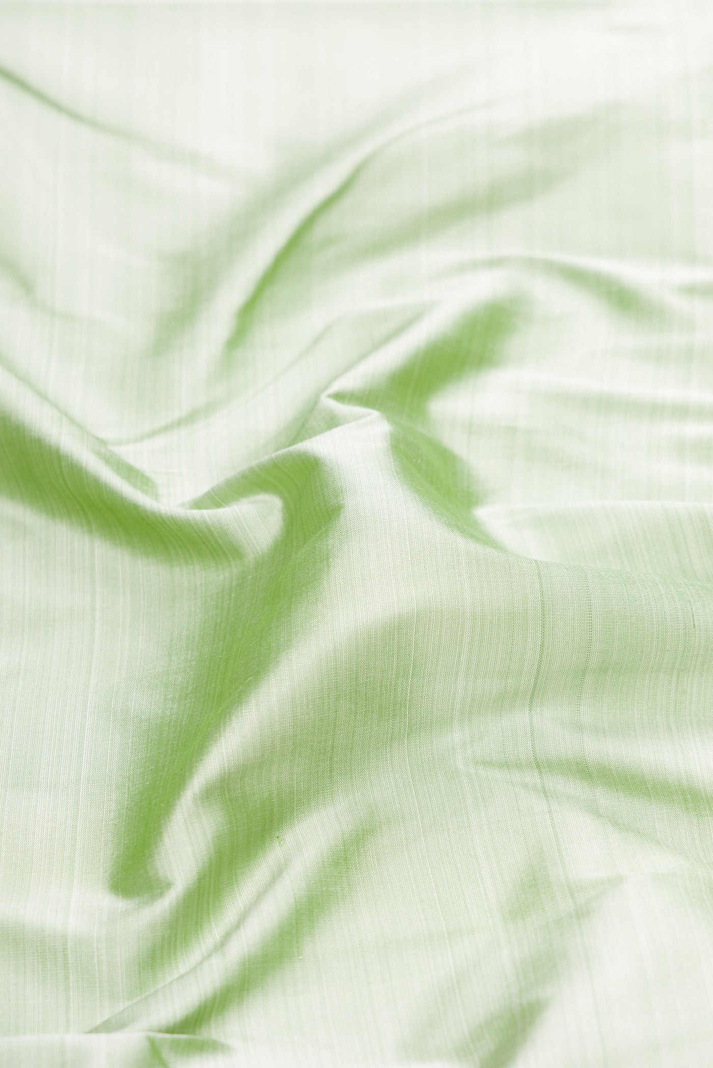 Close up of Pista Green Kanchipuram Silk Saree with Plain Body and Zari Border.  displaying folds