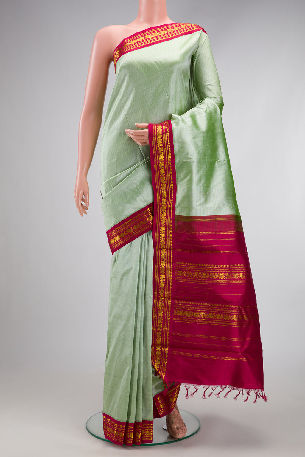 Pista Green Kanchipuram Silk Saree with Plain Body and Zari Border.  displayed on a mannequin