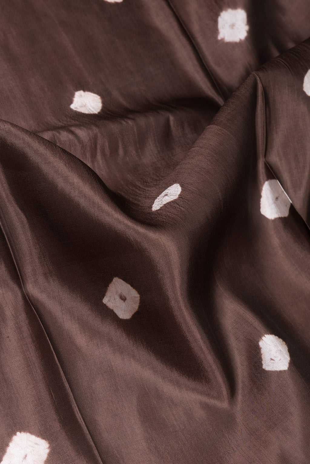 Close up of Brown Blended Tussar Silk Saree with Printed design on the body and Zari Border.  displaying folds