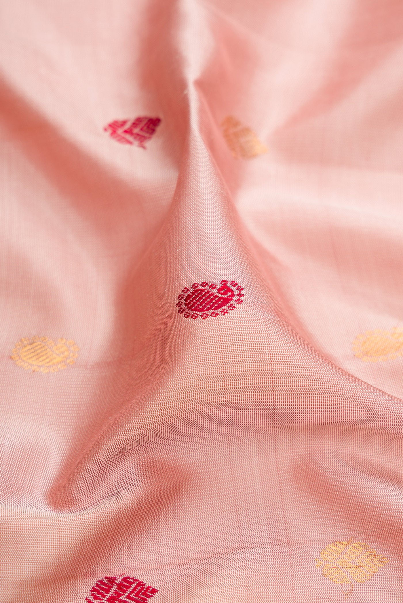 Close up of Rose Gold Gadwal Silk Saree with Zari And Thread Butta on the body and Temple Border.  displaying folds