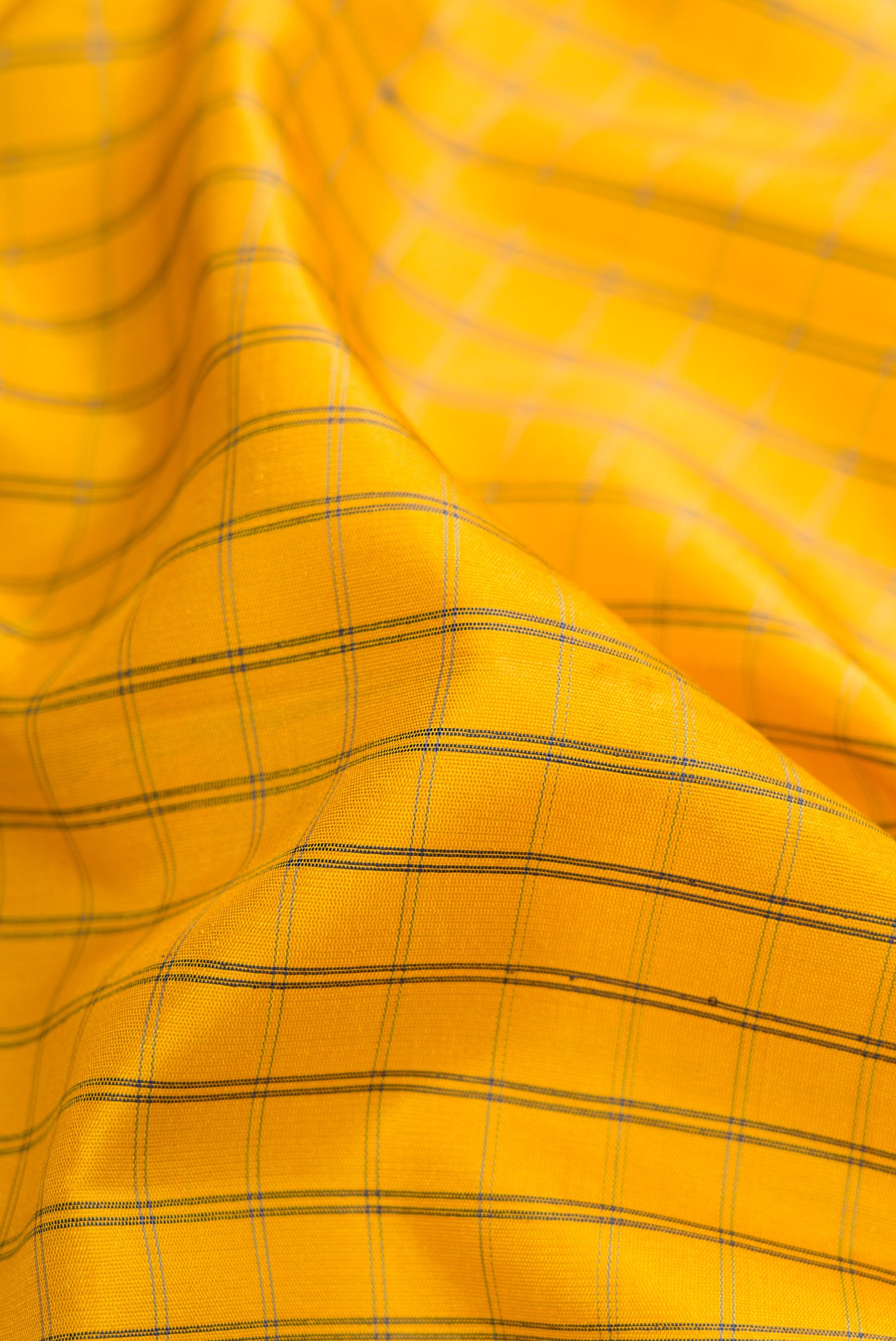 Close up of Yellow Gadwal Silk Saree with Checked design on the body and Temple Border.  displaying folds