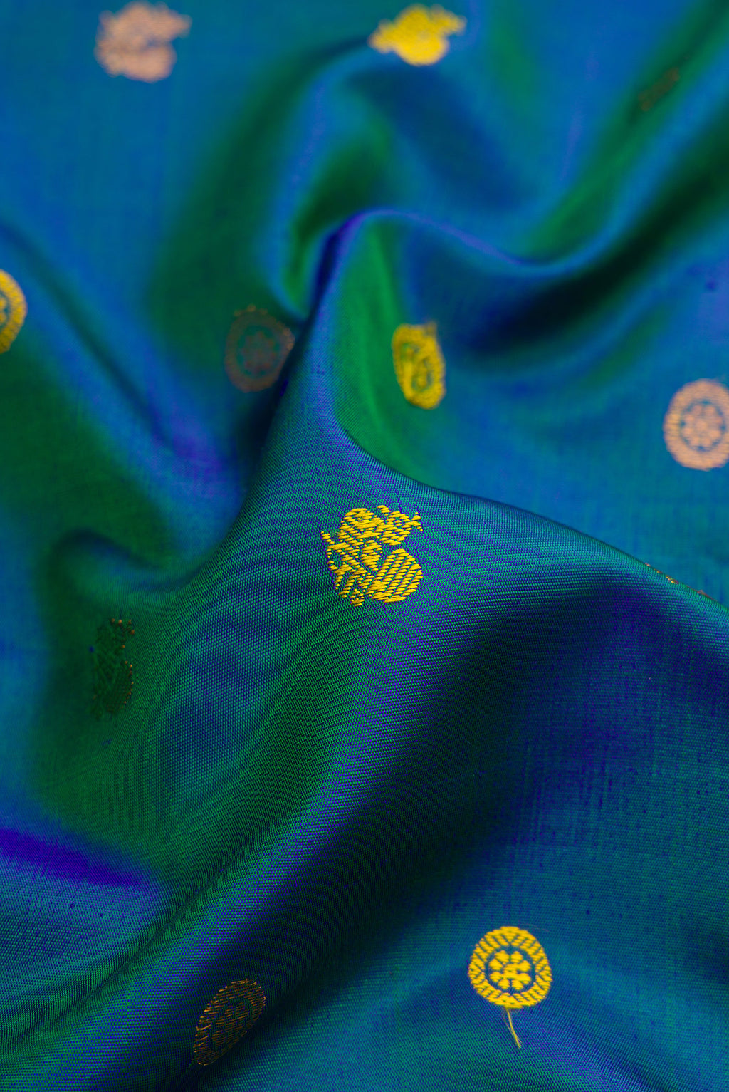 Close up of Peacock Blue Gadwal Silk Saree with Zari Butta on the body and Temple Border.  displaying folds