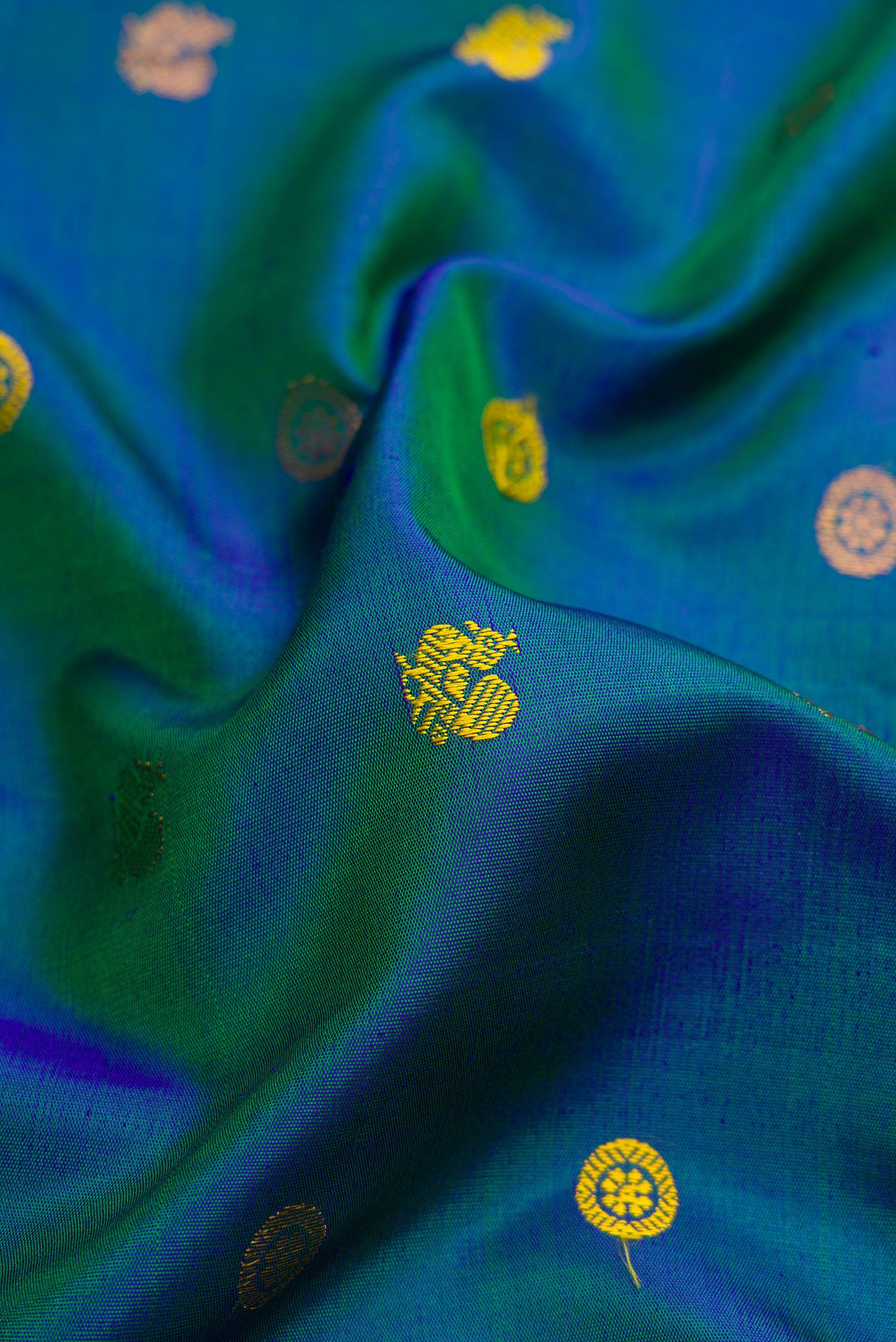 Close up of Peacock Blue Gadwal Silk Saree with Zari Butta on the body and Temple Border.  displaying folds