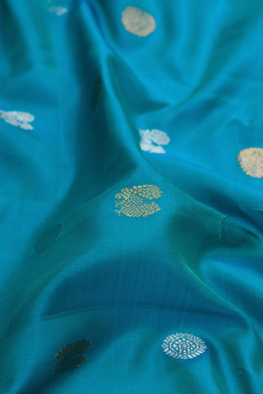 Close up of Peacock Blue Gadwal Silk Saree with Zari Butta on the body and Fancy Border.  displaying folds
