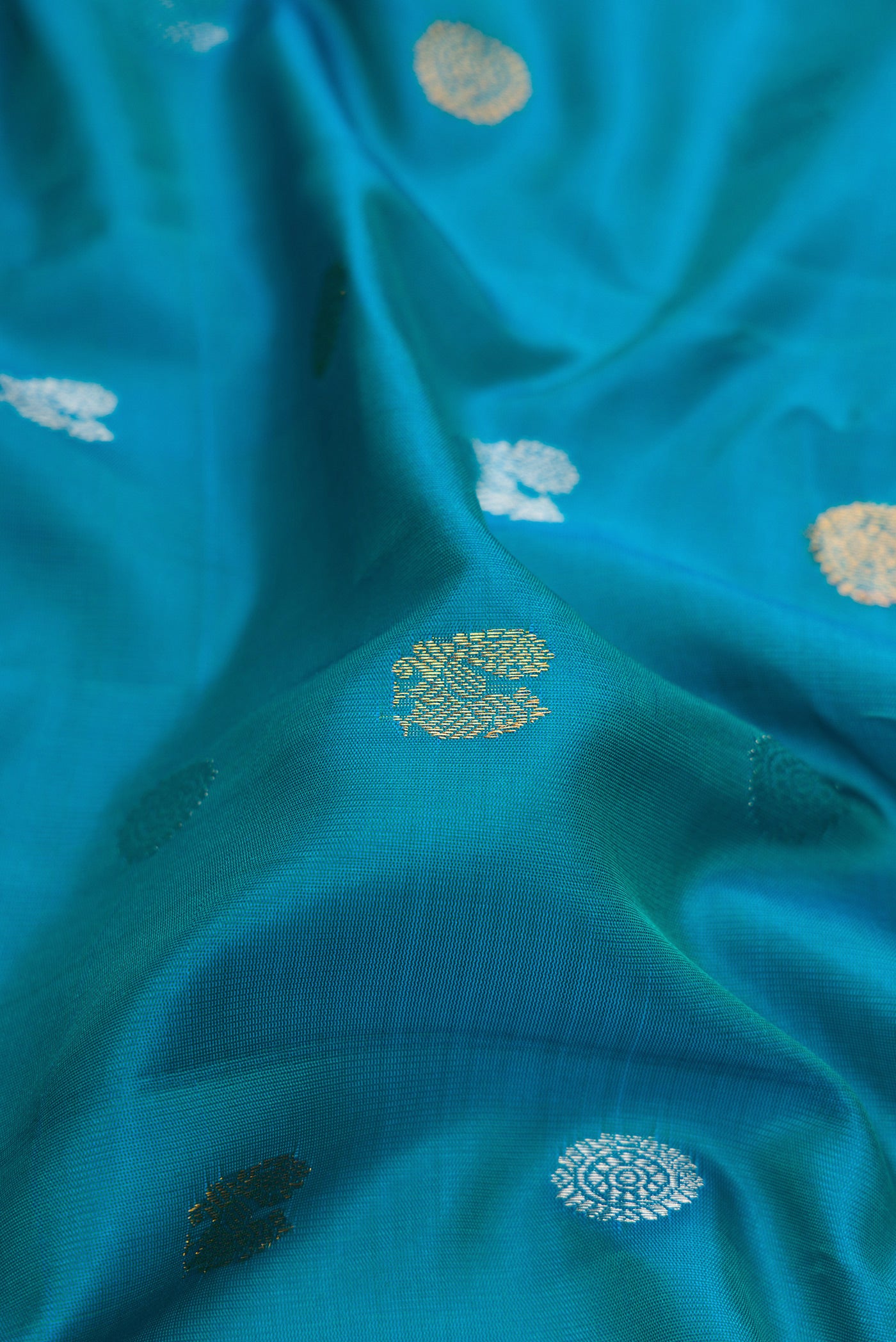 Close up of Peacock Blue Gadwal Silk Saree with Zari Butta on the body and Fancy Border.  displaying folds
