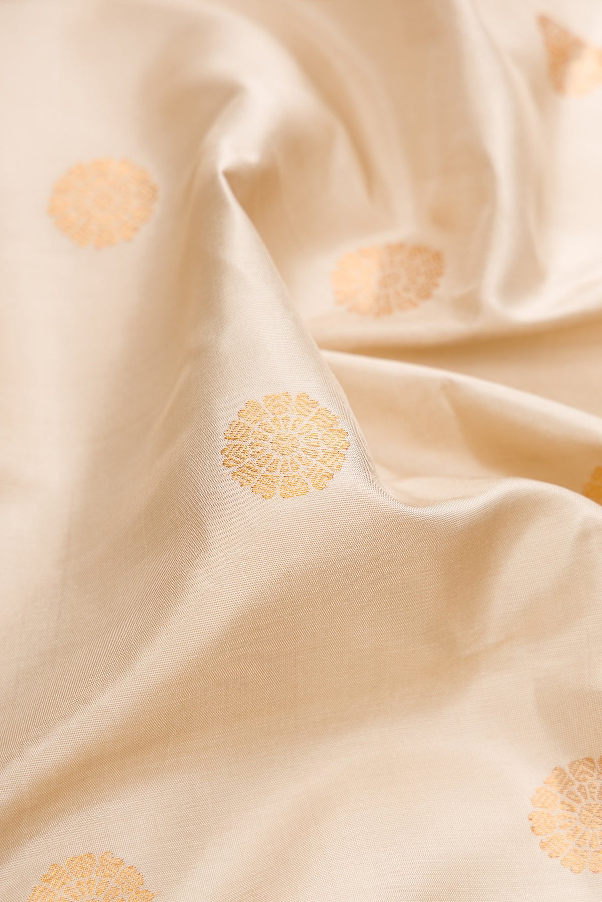 Close up of Cream Gadwal Silk Saree with Zari Butta on the body and Zari Border.  displaying folds