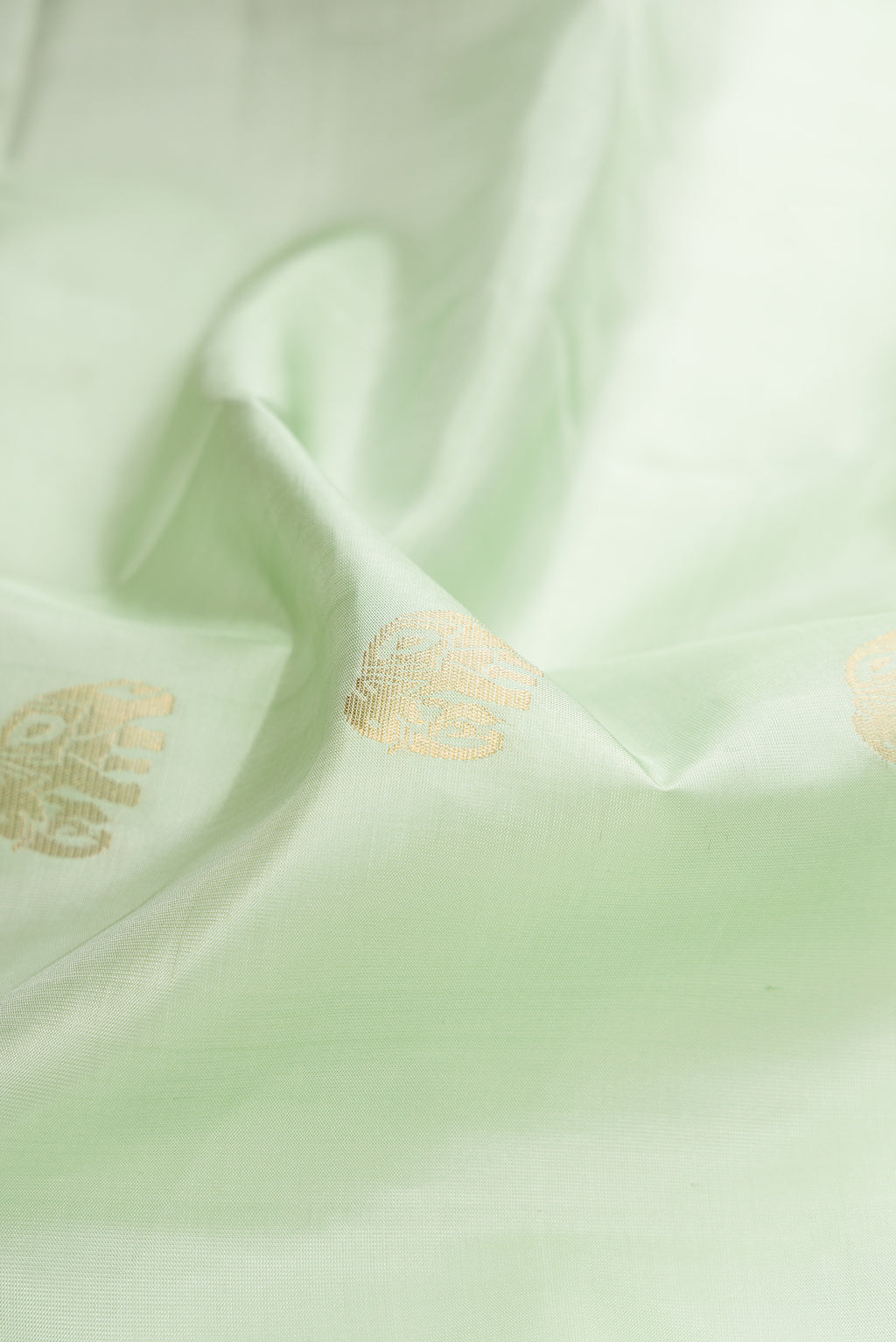 Close up of Pista Green Soft Silk Saree with Zari Butta on the body and Fancy Border.  displaying folds
