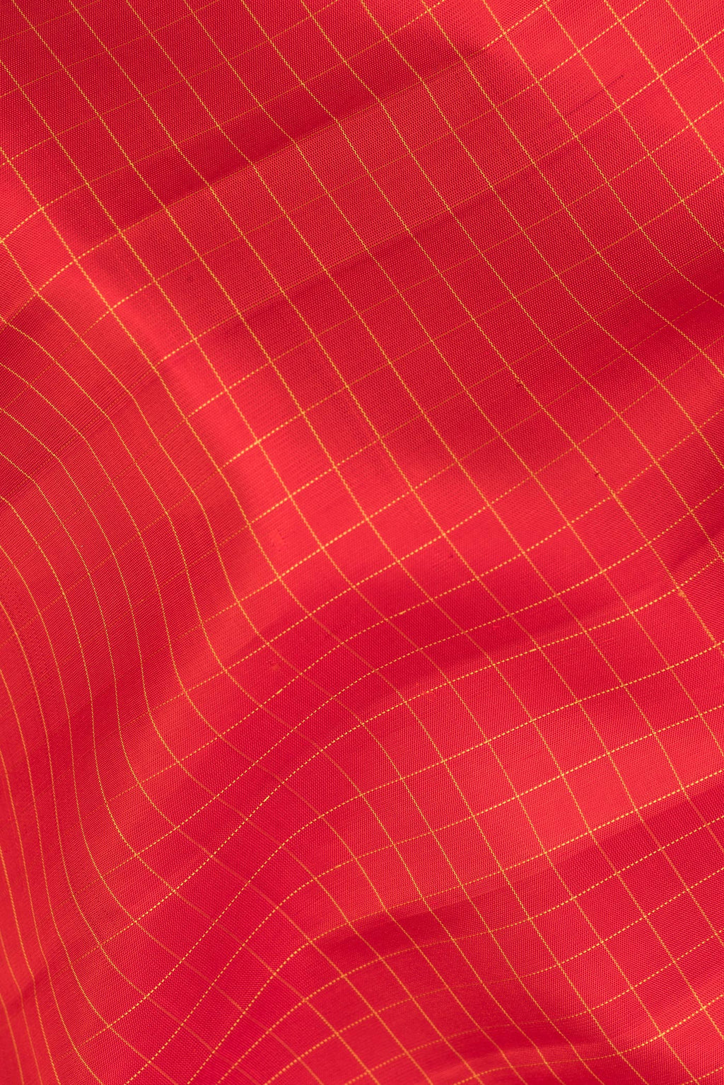 Close up of Pure Silk Red Dual Tone Kanchipuram Saree with Checked design on the body and Zari Border.  displaying folds