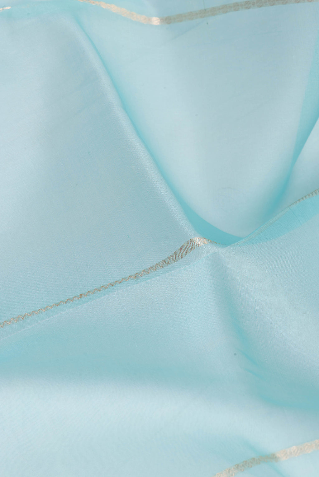 Close up of Light Blue Organza Silk Saree with Stripes on the body and Zari Border.  displaying folds