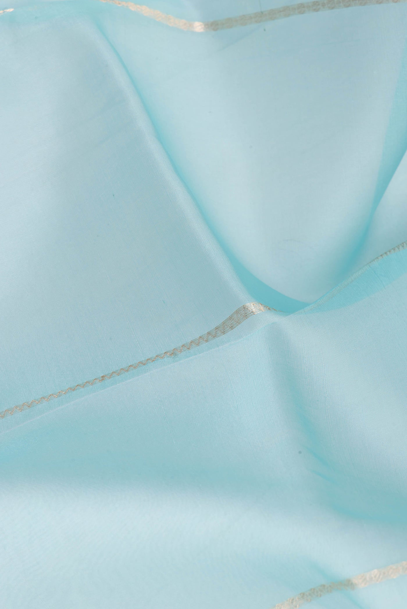 Close up of Light Blue Organza Silk Saree with Stripes on the body and Zari Border.  displaying folds