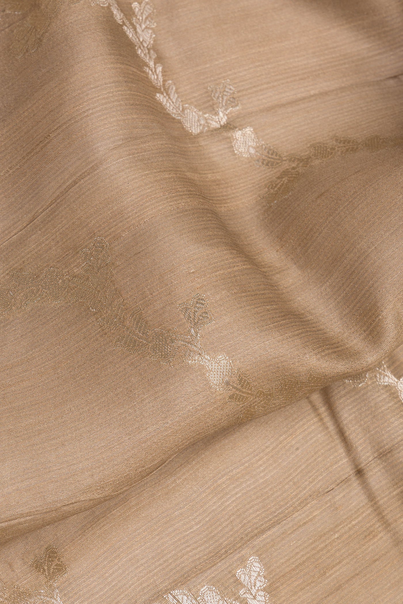 Close up of Dark Beige Tussar Silk Saree with Zari Brocade on the body and Fancy Border.  displaying folds