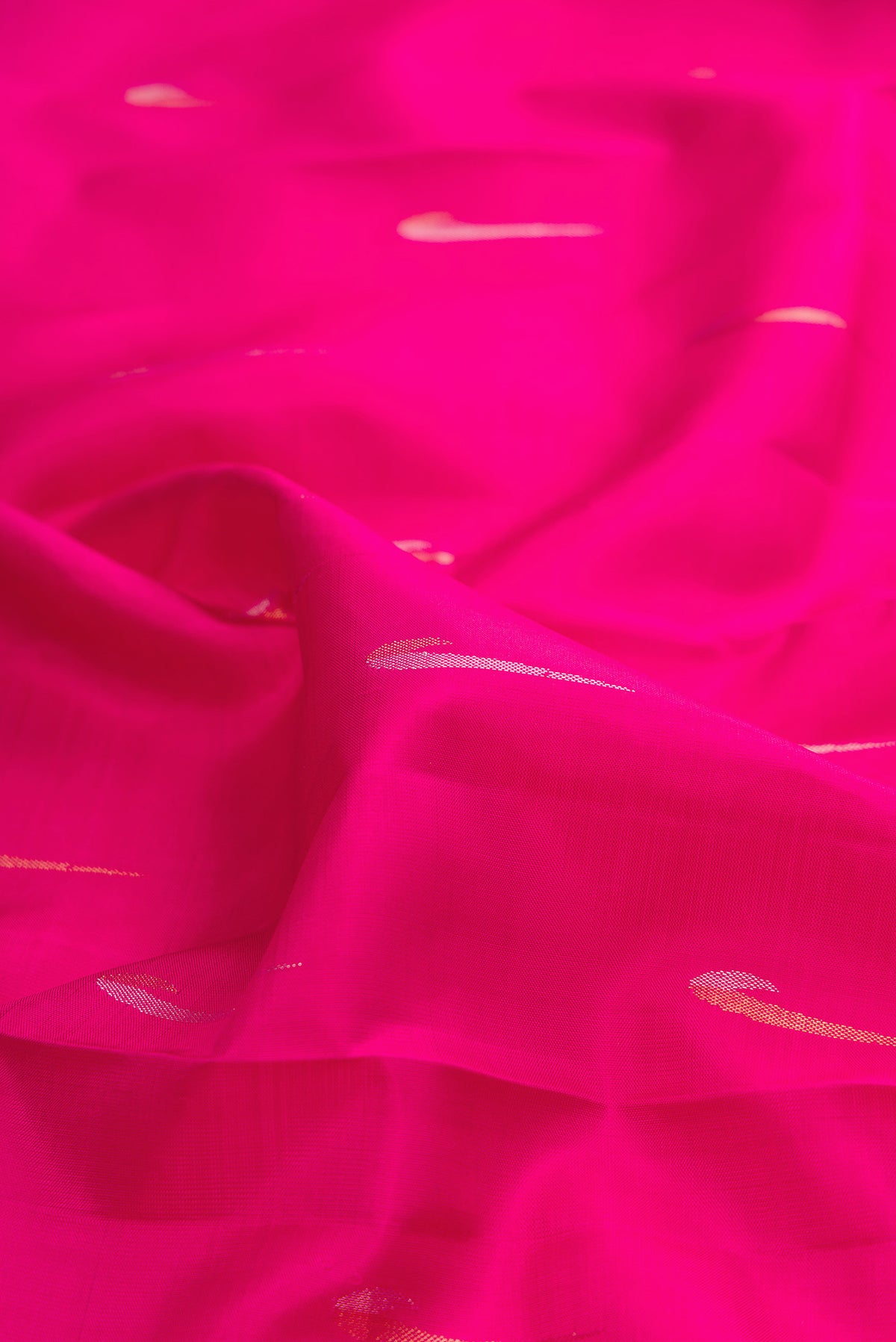 Close up of Pure Silk Rani Pink Kanchipuram Saree with Zari Butta on the body and Zari Border.  displaying folds