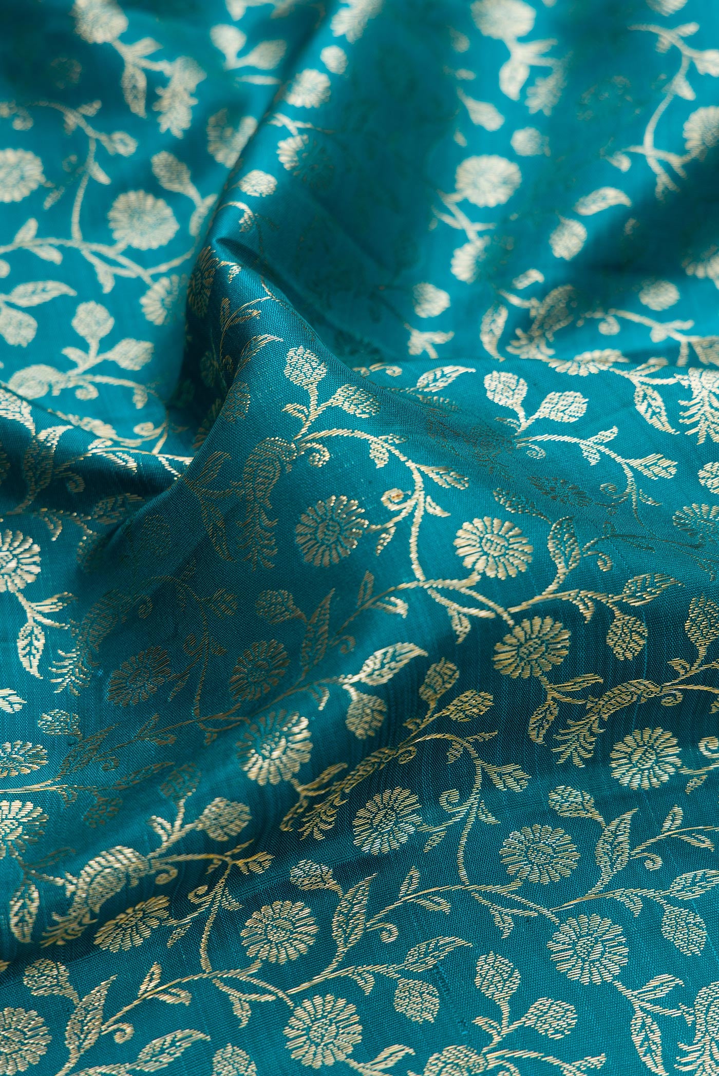 Close up of Teal Kanchipuram Silk Saree with Zari Brocade on the body and Zari Border.  displaying folds