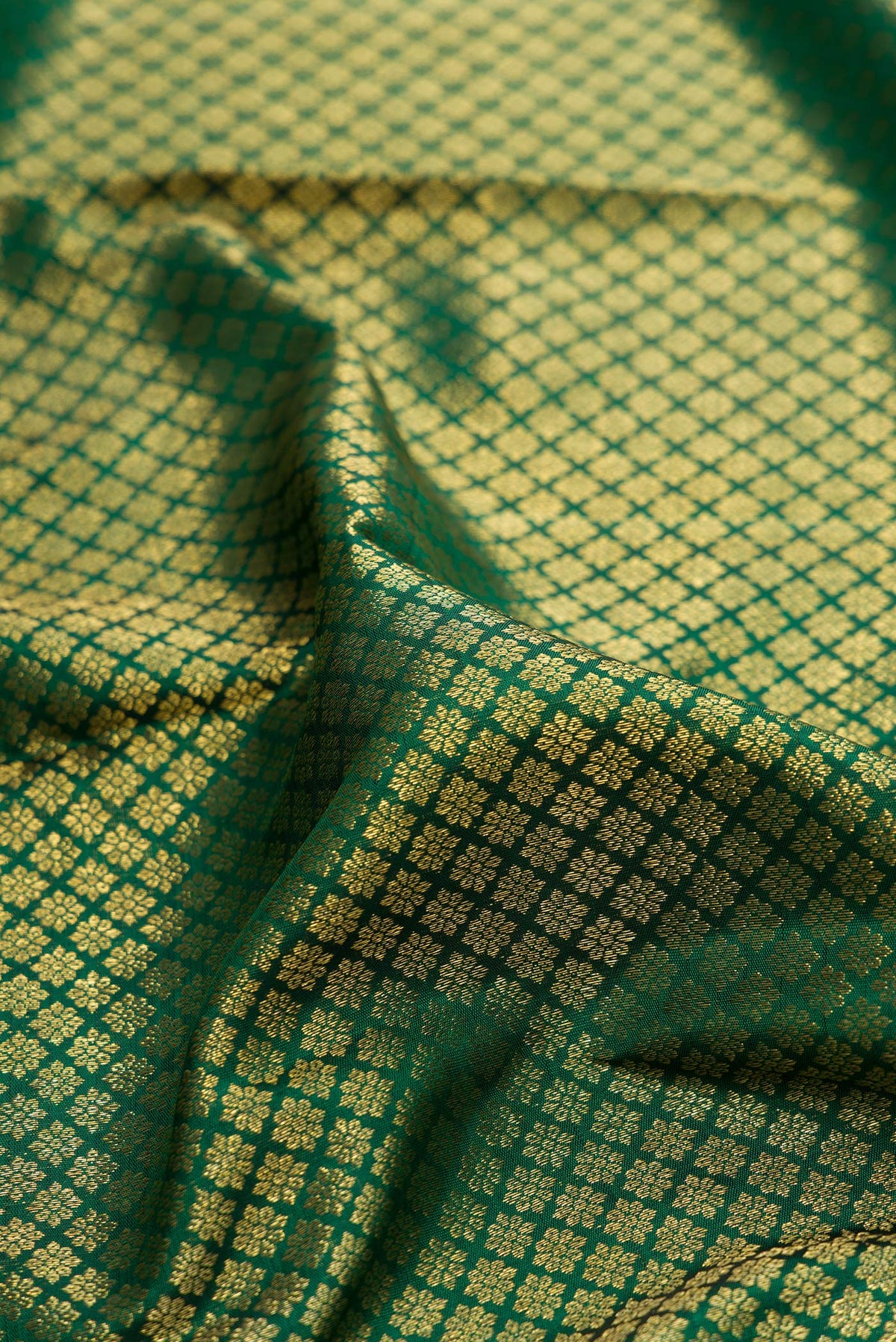 Close up of Pure Silk Bottle Green Kanchipuram Saree with Zari Brocade on the body and Zari Border.  displaying folds