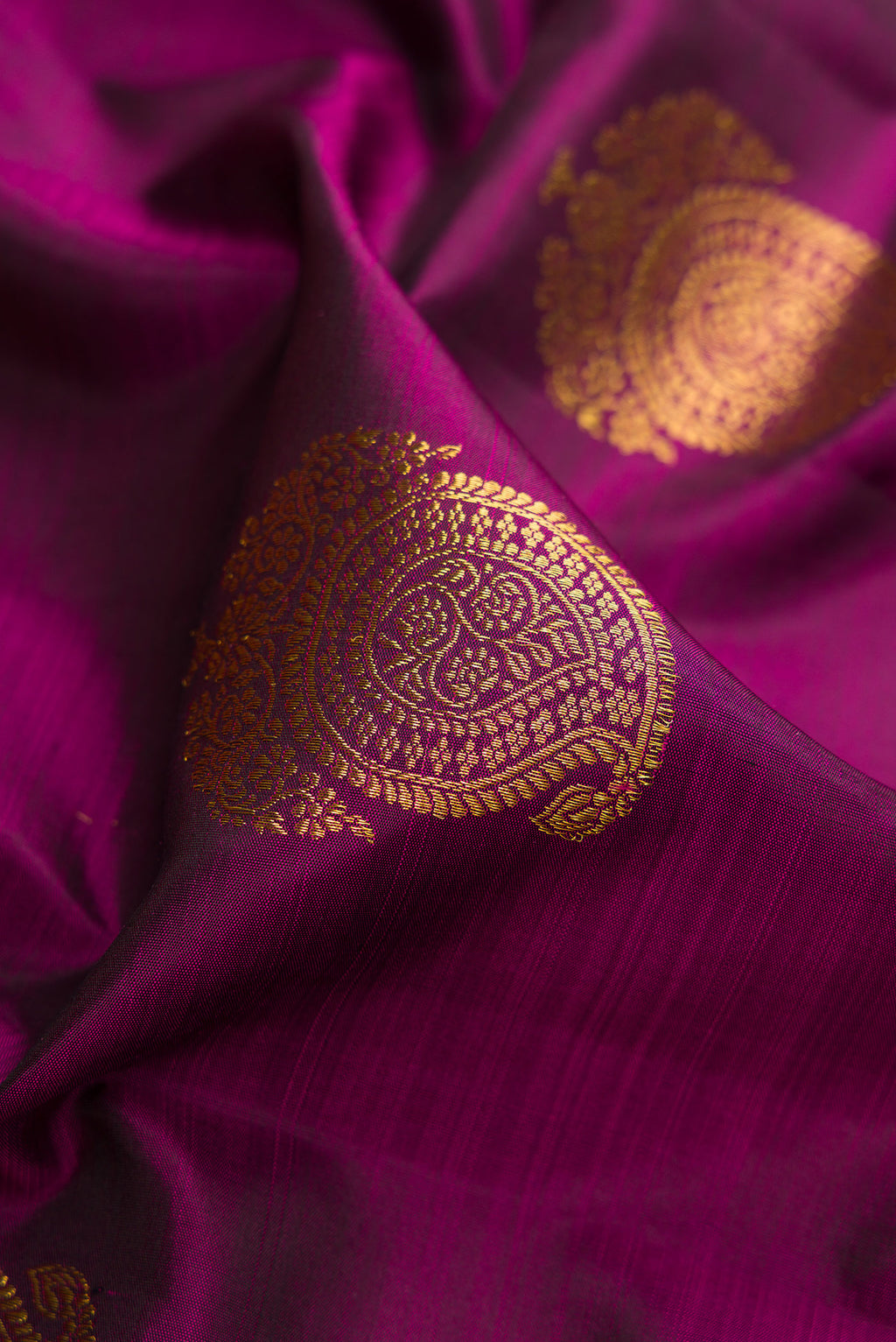 Close up of Magenta Dual Tone Kanchipuram Silk Saree with Zari Butta on the body and Fancy Border.  displaying folds