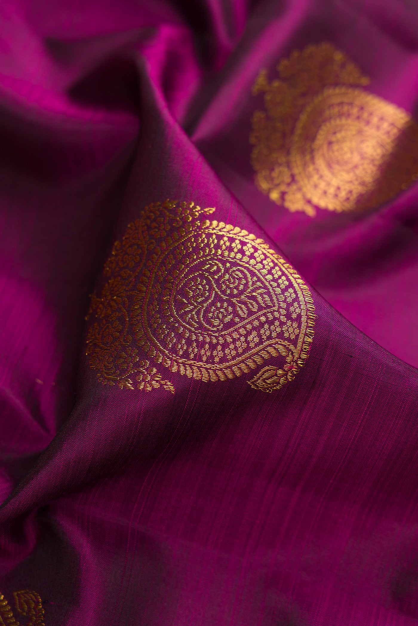 Close up of Magenta Dual Tone Kanchipuram Silk Saree with Zari Butta on the body and Fancy Border.  displaying folds