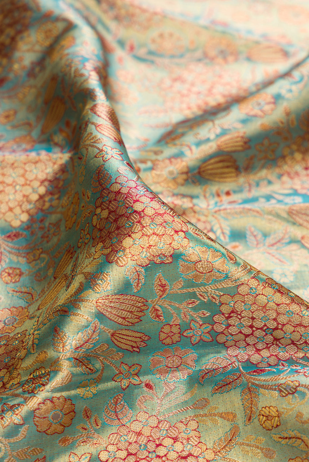 Close up of Turquoise Dual Tone Kanjivaram Tissue Saree with Zari Brocade on the body and Fancy Border.  displaying folds