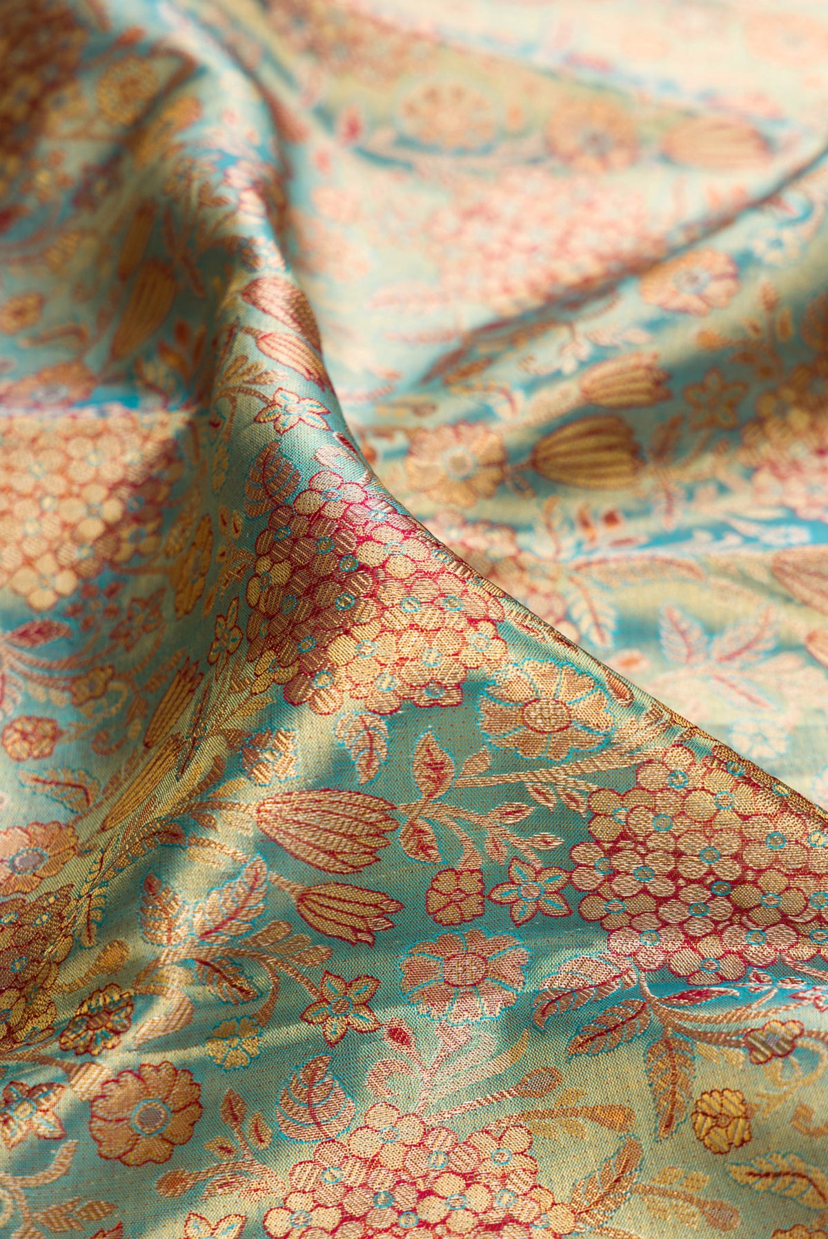 Close up of Turquoise Dual Tone Kanjivaram Tissue Saree with Zari Brocade on the body and Fancy Border.  displaying folds