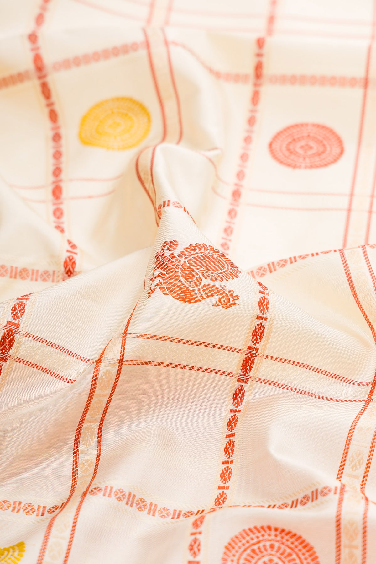 Close up of Cream Kanchipuram Silk Saree with Checked design on the body and Thread Border.  displaying folds