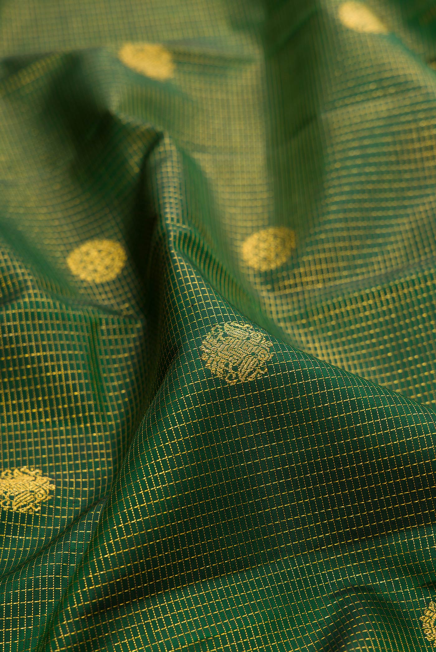 Close up of Bottle Green Kanchipuram Silk Saree with Checked design on the body and Zari Border.  displaying folds