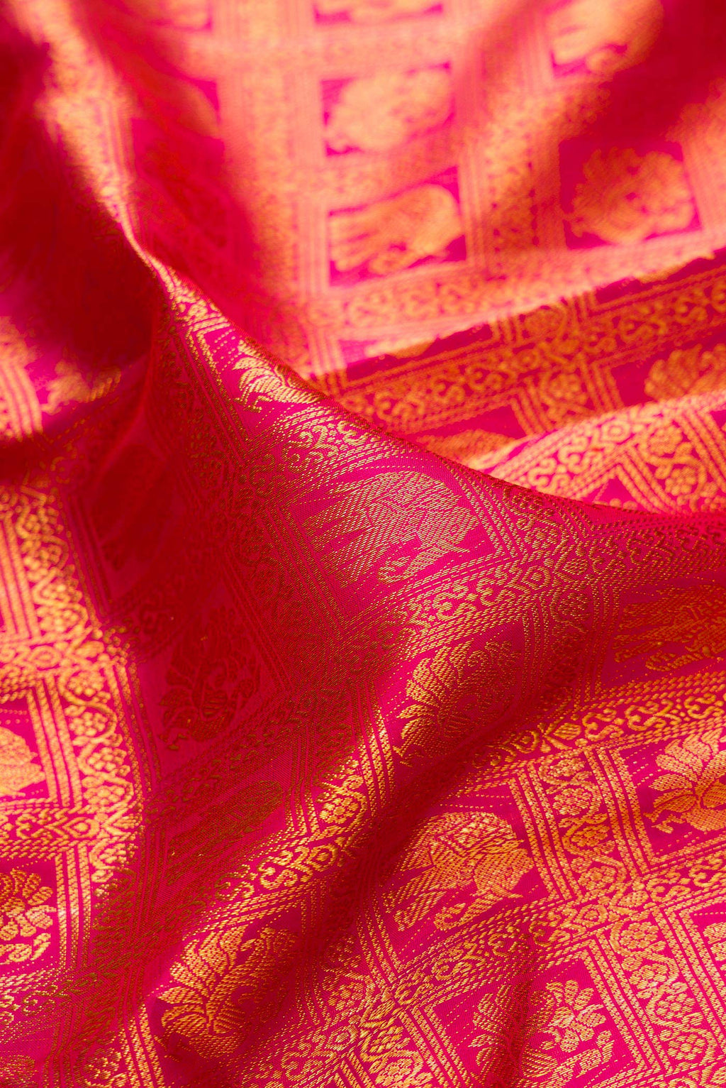 Close up of Rani Pink Kanchipuram Silk Saree with Zari Brocade on the body and Zari Border.  displaying folds