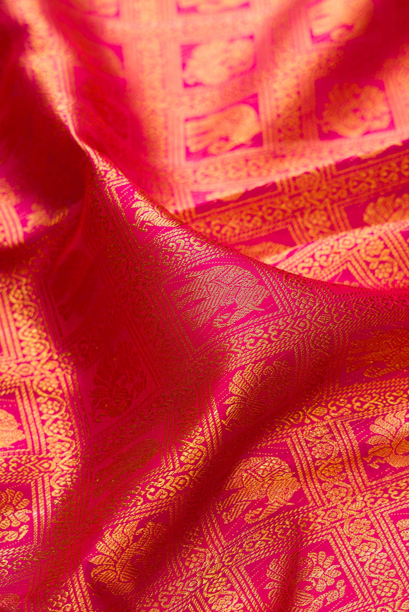 Close up of Rani Pink Kanchipuram Silk Saree with Zari Brocade on the body and Zari Border.  displaying folds