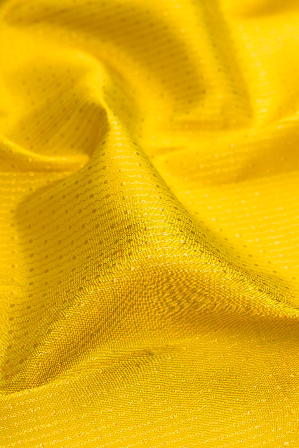 Close up of Yellow Kanchipuram Silk Saree with Zari Butta on the body and Fancy Border.  displaying folds